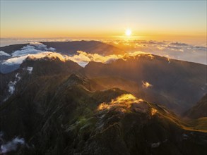 Aerial drone view of mountains over clouds near Pico Ruivo on sunset. Madeira island, Portugal,