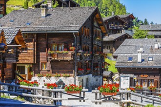 Old wooden houses with wooden shingle roofs and flower boxes in the historic centre of Grimentz,