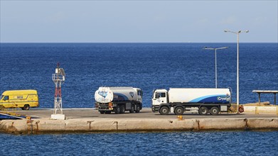 Several lorries standing at the harbour next to the deep blue sea on a clear day, tanker, Pigadia,