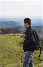 Backpacker looking at a hill in the distance. Portrait of adventurous man looking at a hill from