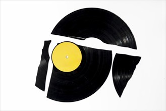 A black record with a yellow label, broken into several fragments