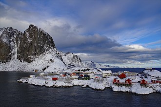 Small settlement with colourful houses on a wintry fjord surrounded by snow-capped mountains,