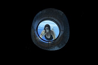 Woman Swimming in the Ship Porthole in Underwater in Swimming Pool in a Sunny Day in Switzerland