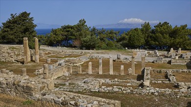 Wide angle shot of ancient ruins with stone columns and trees under blue sky, Ancient well house,