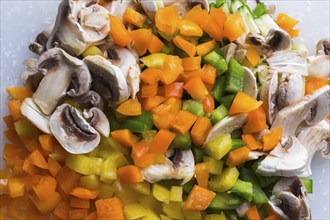 Close-up of diced green, orange and yellow bell peppers, sliced white mushrooms, Studio