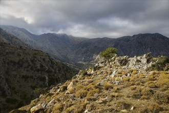 Dark cloud cover hangs over a wild mountain landscape, creating a dramatic feeling of untouched