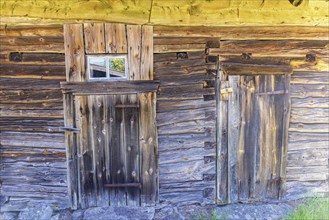 Old weathered log barn with doors and windows on a farm