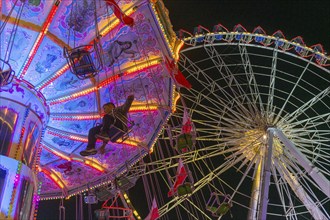 A funfair at dusk with illuminated chain carousel and Ferris wheel, Europa Rad, rides, wave flight,