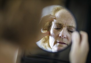 Symbolic photo on the subject of migraines and headaches. A woman rubs her aching head with her