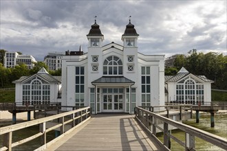 White building complex at the end of a forebridge with wooded background, Rügen