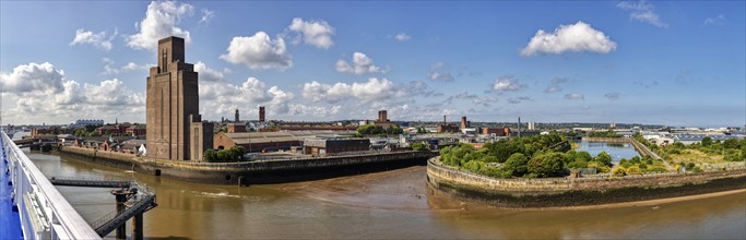 Industrial building by the river with cloudy sky and green nature, Liverpool