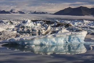 Ice floes, icebergs, reflection, mountains, clouds, sunny, Jökulsarlon, Vatnajökull, Iceland,