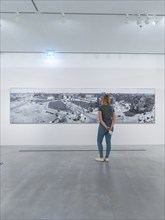 An art gallery exhibiting modern artworks with a viewer looking at a large painting, Berlin,