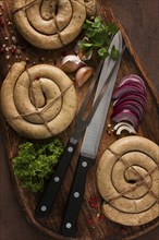 Raw spiral sausages, on a wooden board, top view, with spices, no people