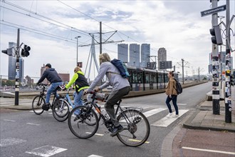 Cyclists on a cycle path on the Erasmus Bridge in Rotterdam, in the background high-rise buildings