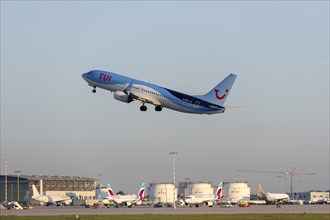 A TUI plane takes off from the airport, the sky is clear and blue, other planes and airport