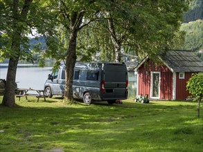 Camper van on a campsite at the Sognefjord, typical red wooden shed, summer, Norway, Europe