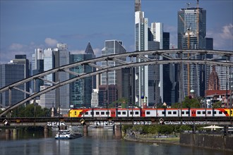 Main with regional railway on the Deutschherrnbrücke and a cargo ship in front of the skyline of