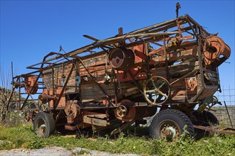 Rusty old combine harvester on green fields under blue sky, wrecked vehicle, Crete, Greek Islands,