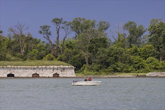 Anglers in their boat on the banks of the Giudecca Canal. Forest and a fortification in the