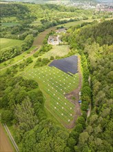 Aerial view of solar installations in a green landscape on the edge of a forest in a rural setting,