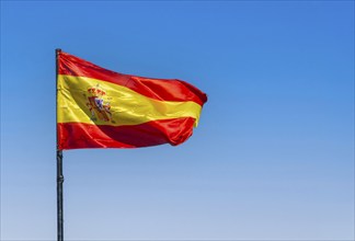 Spanish flag waving in the wind against a blue sky, Ronda, Andalusia, Spain, Europe