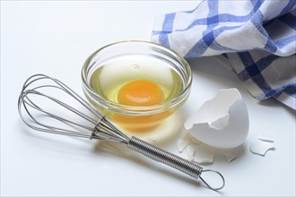 Egg whites and egg yolks in glass bowl and egg shells, whisk