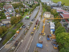 An aerial view of a construction site next to railway tracks with cranes and machines as well as