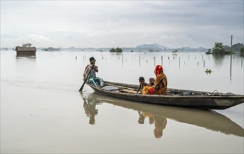 Morigaon, India. 4 July 2024. People travel in a boat to cross a flooded area, in a flood affected