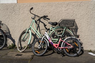 A child's bicycle and a bicycle for an adult are parked together, parked