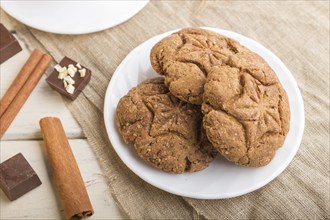 Homemade oatmeal cookies with a cup of cocoa on a linen textile and white wooden background. side