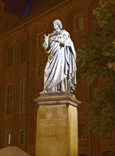 Monument to Nicolaus Copernicus in the medieval old town of Thorn, illuminated in the evening. The