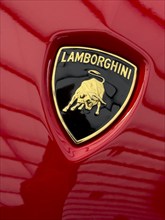 Logo with Lamborghini lettering and stylised fighting bull from sports car manufacturer on red