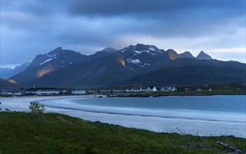 The village of Ramberg with sea and sandy beach. Mountains behind it. Individual sun spots in the