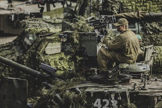 A soldier sits on a tank, taken as part of a Bundeswehr exercise with armed forces from Norway and