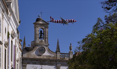 Condor holiday plane, aeroplane, flies low over city archway, stork nests, nest, storks nesting on