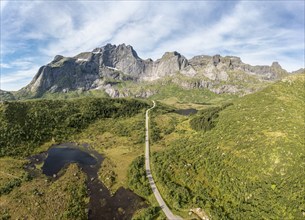 Panoramic aerial view of road in mountain scenery, passing lakes and meadows, road from E10 to