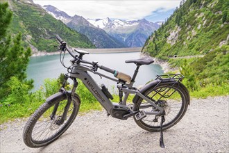 Bicycle standing on a hiking trail with a view of a lake and surrounding mountains in nature, Klein