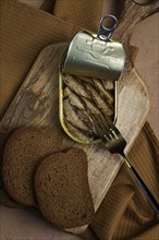 Sprats in butter, with black bread, canned smoked fish, open, close-up, top view, no people