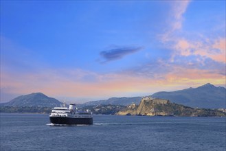 Italy, scenic sunset over Procida Island near Naples with boat approaching it from afar, Europe