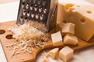 Grated cheese, Maasdam, on a cutting board, grater and cheese knife, close-up, no people