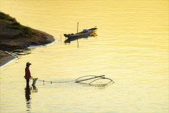 Fisherman with a sinking net at sunset on the Mekong, Luang Prabang, Laos, Asia