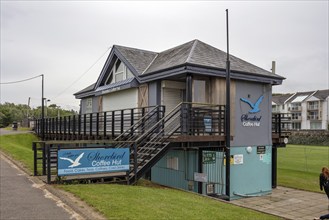 An enclosed café with a wooden façade and staircase, decorated with an image of a seagull,