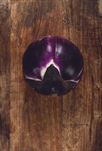 Purple and white eggplant, spherical shape, on a wooden board, top view, raw eggplant, no people