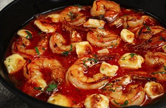 Greek saganaki, in an iron pan, saganaki with shrimp, shrimp in tomato sauce, with pepper and feta