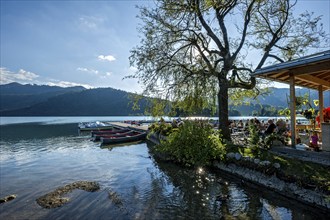 Boats at jetty, boat hire and beer garden, shore of Schliersee, bright backlight, Markt Schliersee,