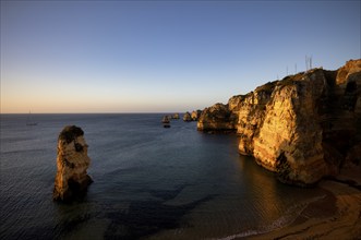 Sailing ship, coloured cliffs and rocks at sunrise on the beach, Praia da Dona Ana, Lagos, cliffs,