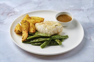 Tender baked cod is paired with vibrant green beans and crispy roasted potato wedges. A savory