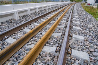 Close-up of rails in a curve, enclosed by rocky ballast and a railing, track construction, rail