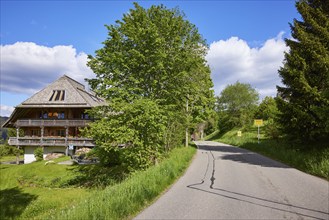 Entrance to the village with Black Forest house, road and village entrance sign to the Oberlehen